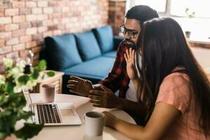 Latino or indian man and woman couple use their laptop in the living room to make video calls. Video call and online chat with family photo