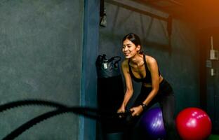 Exercise with a rope swing arm exercises young women's arm muscle building in the gym and smiling happily and bravely photo