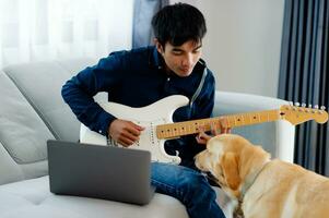 Guitarist playing guitar on sofa at home Practicing guitar at home Relax by playing stringed instruments. photo