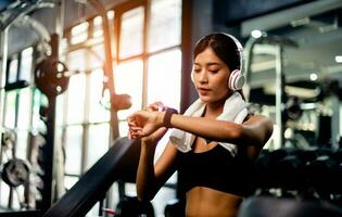 Asian woman wearing workout clothes with over ear music headphones Looking at exercise time create energy for exercise schedule a workout health care process and daily life of single women photo