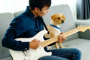 Guitarist playing guitar on sofa at home Practicing guitar at home Relax by playing stringed instruments. photo