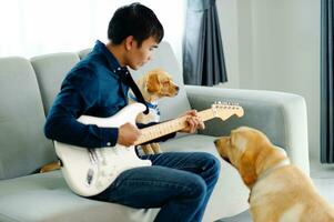 Guitarist playing guitar on sofa at home Practicing guitar at home Relax by playing stringed instruments. photo