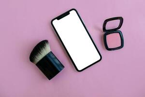 Mockup, smartphone, brush and blush on a pink background. photo