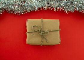 Navidad antecedentes con un regalo. un regalo en arte papel y plata oropel en un rojo antecedentes. foto