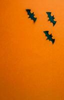 Halloween background, paper black bats on orange background, vertical background. photo
