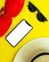 Bosquejo, teléfono inteligente, Gafas de sol, traje de baño y sombrero en un amarillo antecedentes. verano vacaciones, vertical antecedentes. foto