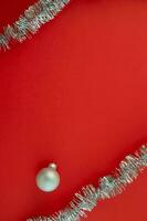 Christmas vertical background with copy space in the center. Silver tinsel and Christmas ball on a red background. photo