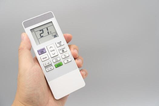 Hand holding air conditioner controller with buttons and display on isolated background. photo