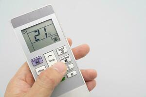 Hand holding air conditioner controller with buttons and display on isolated background. photo