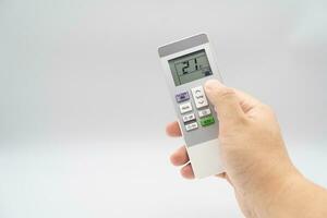 Hand holding air conditioner controller with buttons and display on isolated background. photo