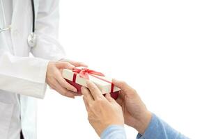 Close up hands of senior old man and the doctor giving gift box. senior's hand receives a gift box from doctor. Medical health care. photo