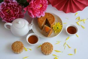 Top view of Chinese Mid-Autumn Festival concept made from mooncakes, tea decorated with plum blossom on white background. photo