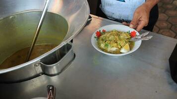 soto lamongan seller prepares a menu at his stall photo