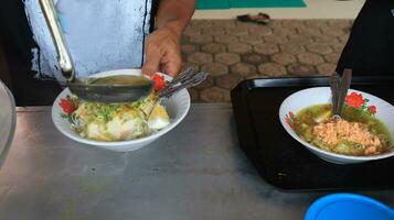 soto lamongan seller prepares a menu at his stall photo