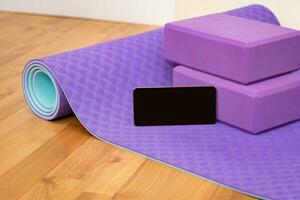 Blank phone on yoga mat with blocks photo