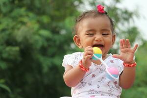 linda sur indio bebé niña jugando con vistoso traqueteo juguete. foto