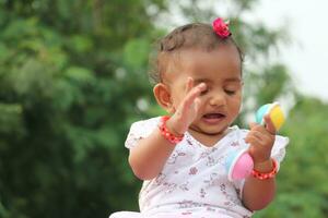 linda sur India bebé niña jugando con vistoso juguete en el parque foto