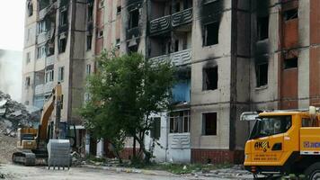 Demolition of a high-rise building. House collapse. Construction work on the demolition of multi-storey apartments. Fence made of red and white warning tape. Ukraine, Irpin - May 12, 2023. video