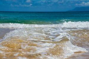 Small waves creating foam on the beach with white sand, hot day and calm sea, Mahe Seychelles photo