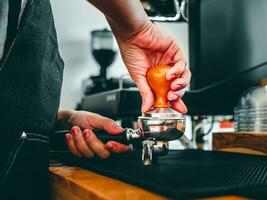 Close-up of hand Barista cafe making coffee with manual presses ground coffee using a tamper at the coffee shop photo