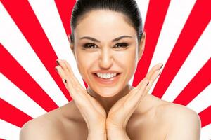 Cheerful beautiful woman face portrait close up over red and white geometric background. Beauty skin care concept. photo