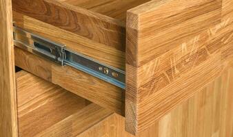 Opened drawer with a slider close view photo, wooden eco furniture elements background. Solid wood furniture details photo