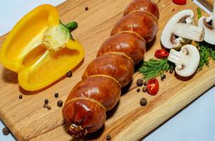 Tasty sausages and vegetables isolated over solid background photo