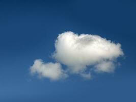 Single white cloud over blue sky background. Fluffy cumulus cloud shape photo