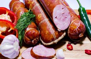 Tasty sausages and vegetables isolated over solid background photo