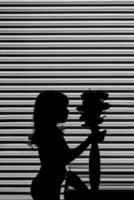 a silhouette of a girl holding a vase of flowers photo