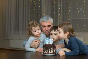 un hombre y Tres niños sentado alrededor un pastel foto