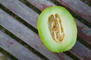 a melon cut in half on a wooden bench photo