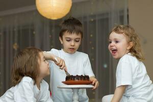 Tres niños sentado en un mesa con un pastel foto