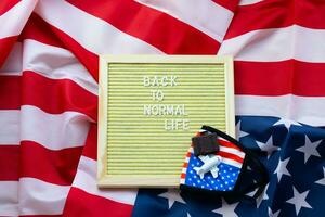 Back to normal life sign with flag face mask photo