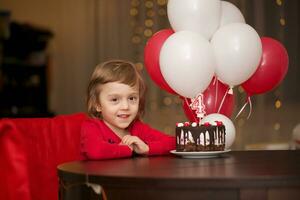 a little girl sitting at a table with balloons photo