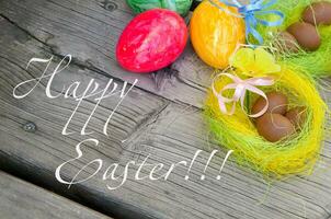 easter eggs and nest on wooden background with happy easter text photo