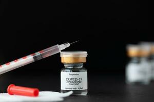 a syringe with a vial of vaccine and a needle photo