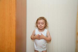 a little boy in a white shirt standing in front of a door photo