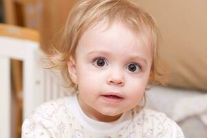 a baby sitting in a crib with a toy photo