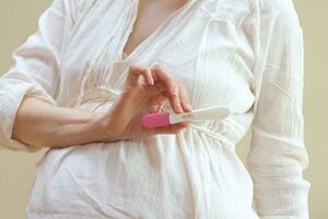 a pregnant woman holding a pink toothbrush photo