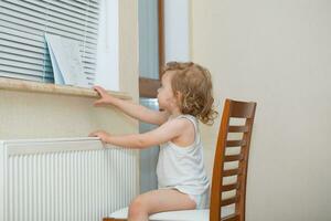 a little girl sitting on a chair near a window photo