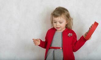 Girl of two years old in red gray costume with a present photo