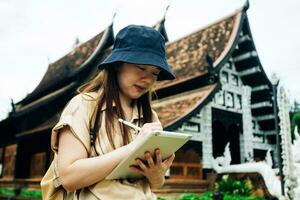 Asian traveller woman with tablet at ok moli temple in Chiang Mai province, Thailand photo