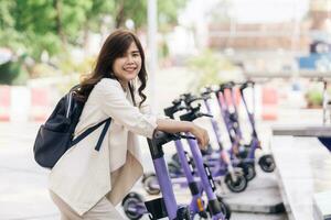 retrato de joven asiático mujer montando eléctrico scooter en parque foto