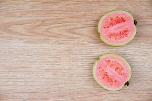 Flatlay of half cut fresh guava on the wooden table photo