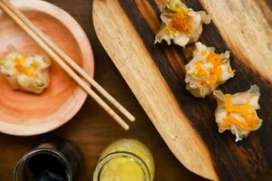 Flat lay of traditional chinese dimsum with sauce and herbs serve on a wooden table photo