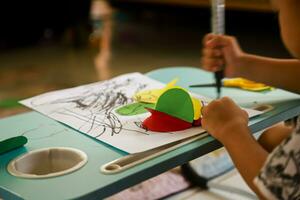 a toddler learning to make paper crafts and make doodles on paper using markers photo