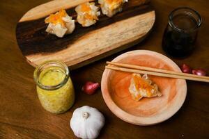 Flat lay of traditional chinese dimsum with sauce and herbs serve on a wooden table photo