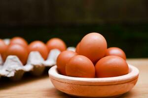 a few chicken eggs are placed in a wooden bowl photo