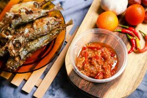 fried mackerel fish served on a plate with spicy sauce photo